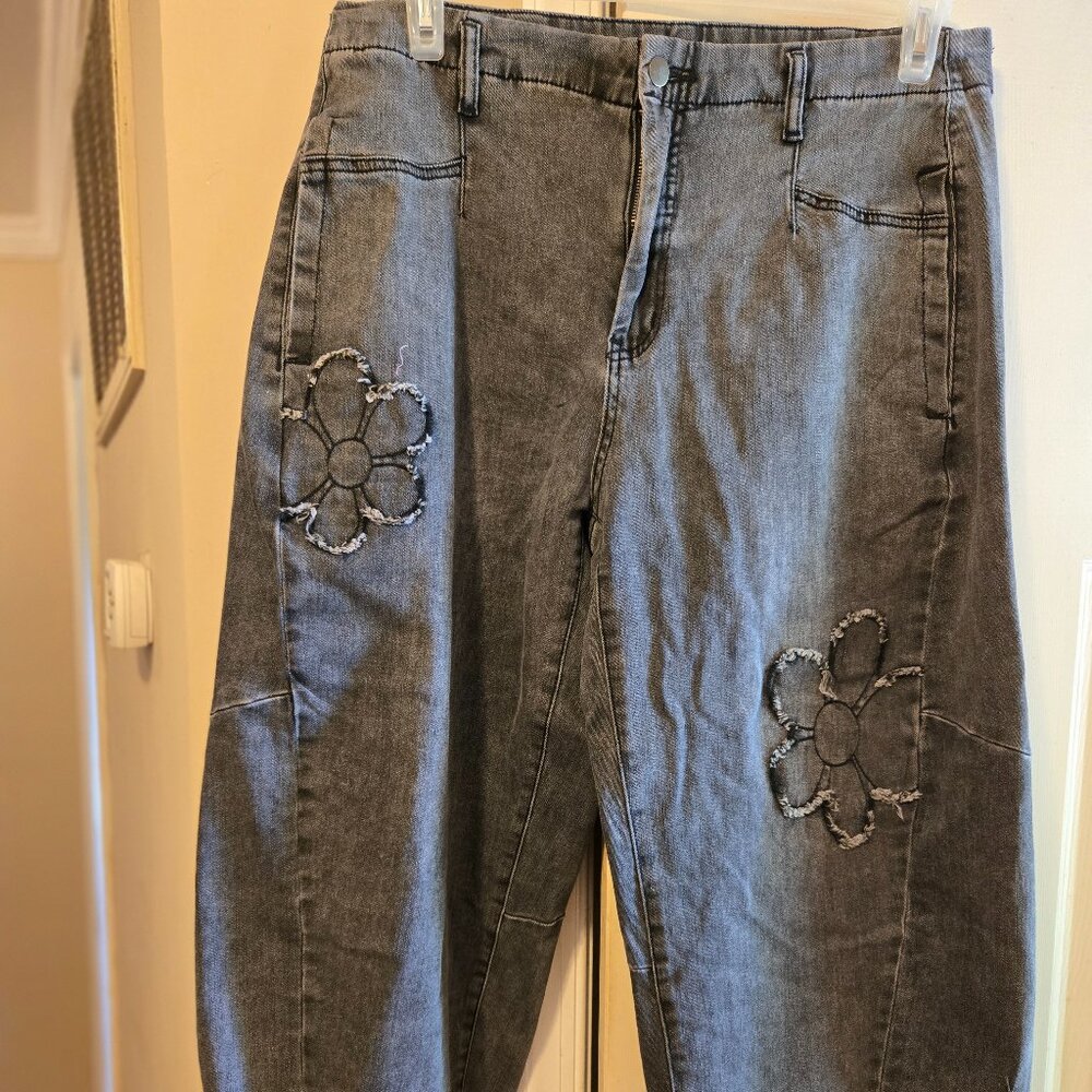 Easel L off black barrel jeans with flower patch accents.